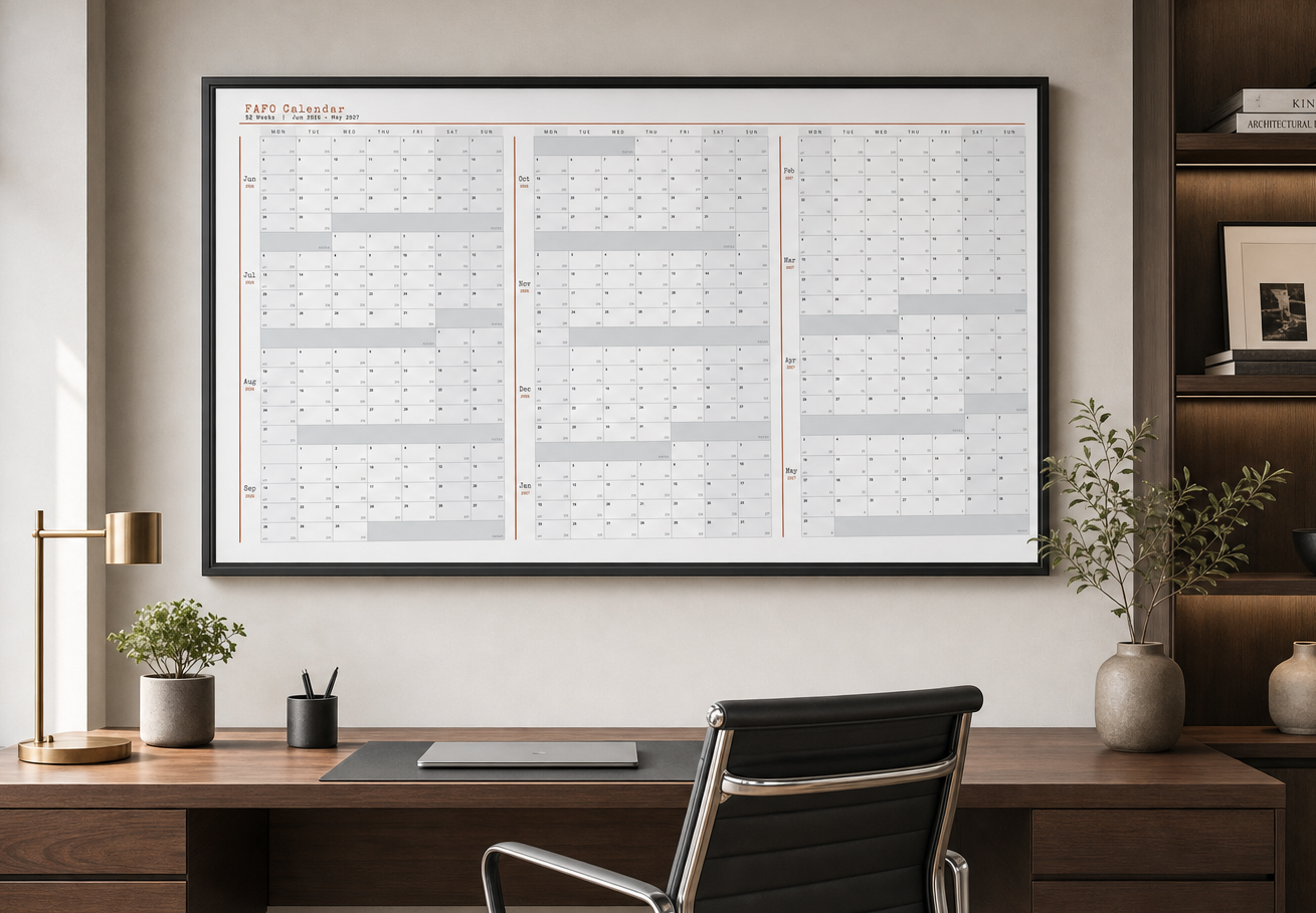 FAFO six-foot dry-erase wall calendar mounted on a white wall, filled in with a full year of color-coded plans in plum and blaze orange.